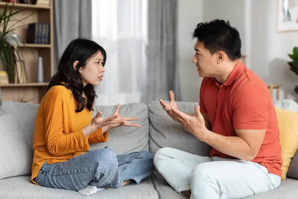 有感情的中国夫妇在家里吵架 愤怒的亚洲丈夫和妻子穿着家居服坐在沙发上 彼此大喊大叫 摆出姿势 感情危机 — 图库照片