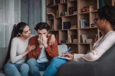 Depresyondaki üzgün Avrupalı eş kocasını sakinleştiriyor. Ofis kliniğinde çalışan bir doktor. Stres, psikolog desteği, profesyonel yardım, aile terapisi, ilişki sorunları, keder ve baskı