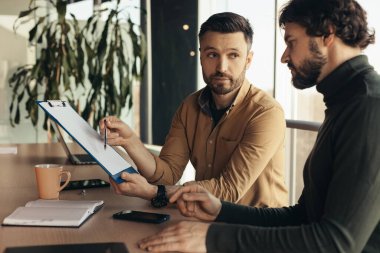 Ortaklık kavramı. Belgeleri inceleyen iki ciddi iş adamı ofis içi iş anlaşmalarını tartışıyorlar. Belgeleri inceleyen, modern şirkette birlikte çalışan girişimciler.