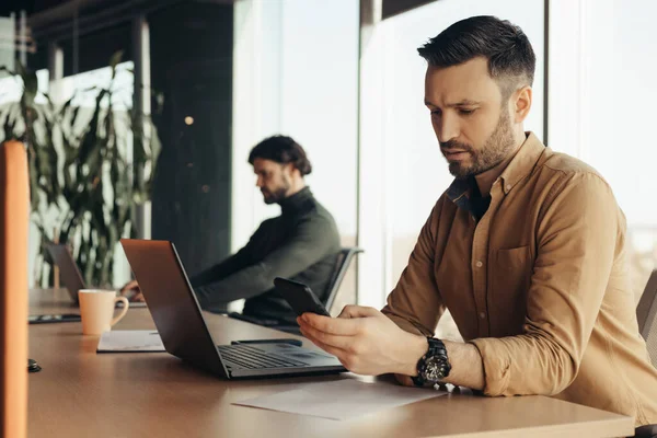 Empregado Sério Empresa Masculina Verificando Telefone Celular Usando Laptop Trabalhando — Fotografia de Stock