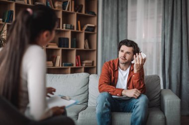 Stres, keder ve baskı. Kafkasyalı genç bayan doktor danışmanlık yapıyor kliniğin içinde peçeteli erkek müşteri ağlıyor. Tıbbi yardım, depresyon tedavisi ve zihinsel sorunlar, destek ve terapi