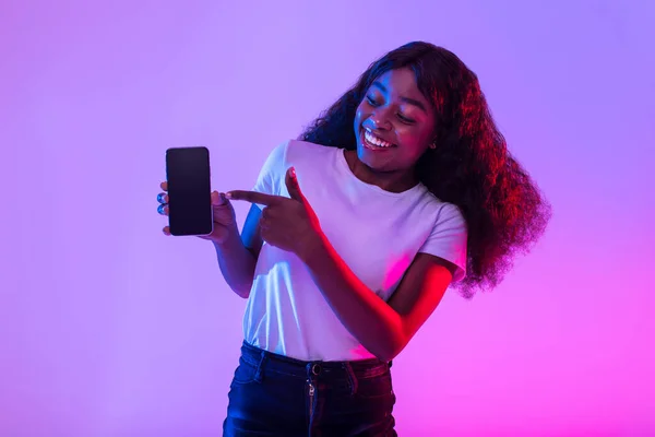 Mujer Negra Joven Positiva Apuntando Teléfono Inteligente Con Pantalla Vacía — Foto de Stock