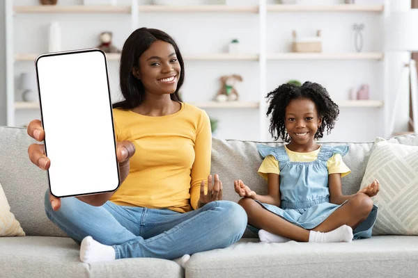 Mobile Offer. Smiling Black Mother And Daughter Showing Big Blank Smartphone With White Screen At Camera, African American Mom And Female Child Sitting At Home Recommending New App, Collage, Mockup