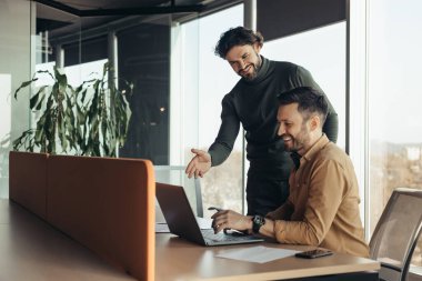 Ortak çalışma konsepti. Laptop bilgisayarında birlikte çalışan iki meslektaşım modern ofiste iş araştırması yapıyorlar, boş alan. Ekip üyesi deneyimli erkek iş arkadaşıyla iletişim kuruyor.