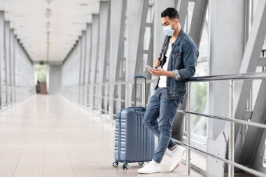 Medikal Yüzlü Genç Eatern Adam Havalimanında Akıllı Telefonla Rahatlıyor, Arap Erkek Terminalde Uçuşu Beklerken Cep Telefonu Kullanıyor, Coronavirus Salgını sırasında Seyahat Ediyor