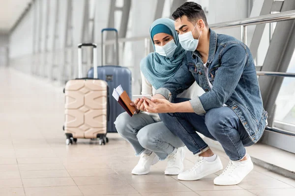 Pareja Islámica Con Máscaras Médicas Usando Smartphone Mientras Esperan Vuelo —  Fotos de Stock