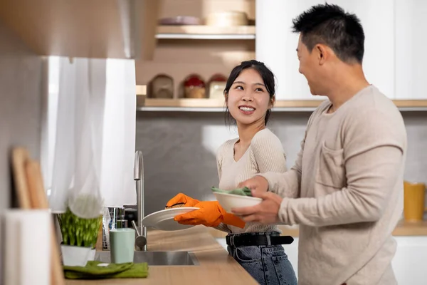 아시아 부부는 부엌의 싱크대에서 설거지를 사람인 아내는 허드렛일을 하면서 대화를 — 스톡 사진