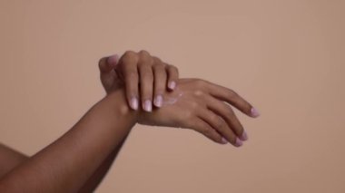 Mevsimsel cilt nemlendirici. Tanımlanamayan Afrikalı Amerikalı bir kadının bej rengi bir kremle cildini pohpohlaması, yavaş çekim.