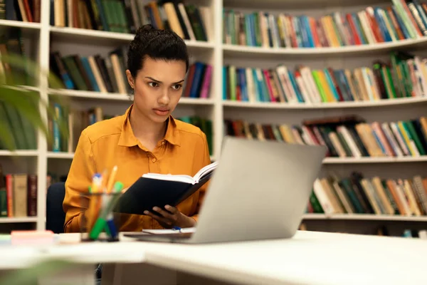 Összpontosított Vegyes Fajú Hölgy Könyvet Olvas Laptopot Néz Online Tanul — Stock Fotó