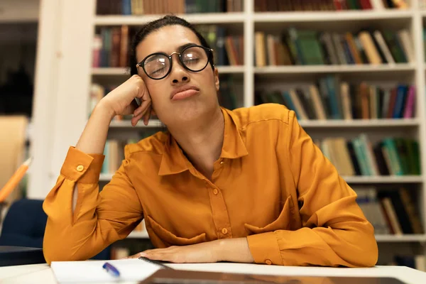 Dizüstü bilgisayarın önünde uyuyan yorgun kız öğrenci, online çalışıyor ya da kütüphanede sınavlara hazırlanıyor. Çevrimiçi çalışmalar sırasında aşırı çalışan bitkin düşmüş melez kadın.