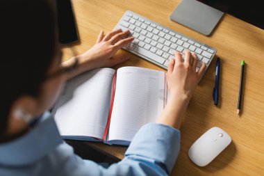 Tanımlanamayan Japon Kadın Bilgisayar Klavyesi Yazı Raporu Kullanıyor ve Modern Ofiste Masada Oturan İş Planlama Programı. Kollara Seçici Odaklanma. Kırpılmış, Yüksek Açı