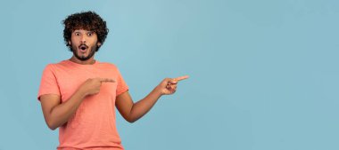 Fotokopi odasını gösteren pembe tişörtlü, kıvırcık saçlı ve sakallı, mavi stüdyo arka planında tek başına poz veren, reklam ya da metin için boş alan gösteren,