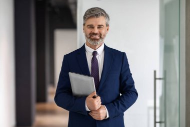İş adamı. Ofiste dizüstü bilgisayarı olan yakışıklı bir iş adamının portresi, kendine güvenen yetişkin girişimci kameraya gülümseyen, boşluğu kopyalayan