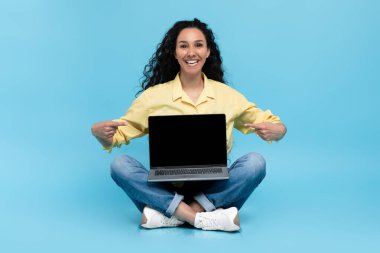 Şu web sitesine bak. Güzel genç bir kadın boş ekranlı dizüstü bilgisayarı işaret ediyor. Mavi stüdyo arka planında bacak bacak üstüne atmış oturuyor. Çevrimiçi reklam için boş alan gösteren mutlu milenyum kadınları