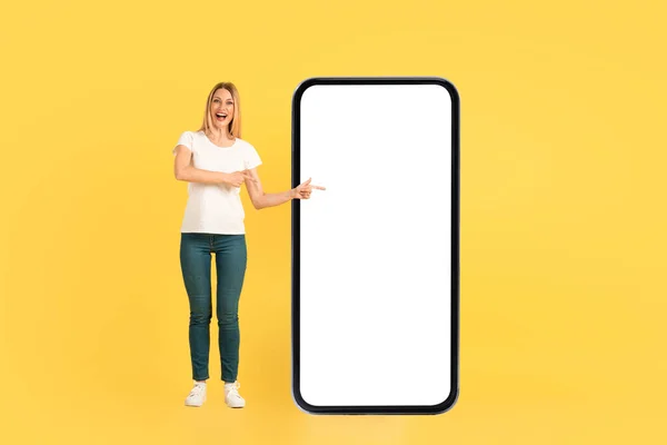 快乐的千年期高加索女性 穿着白色T恤 嘴尖手指张开 巨大的手机与空白屏幕 孤立在黄色背景 新的应用程序 梦幻般的数字广告和提供 — 图库照片