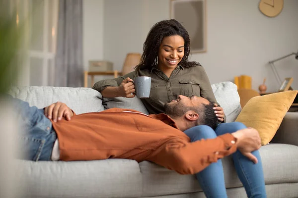 快乐的非洲裔美国夫妇喝咖啡 坐在沙发上聊天放松 享受国内舒适的生活 周末休闲和放松的概念 — 图库照片