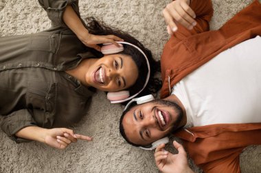 Evde kameraya gülümseyen ve kulaklık takan mutlu siyah çiftin en iyi görüntüsü. Millennial Eş Favori Şarkısı 'nın tadını çıkarıyor. Haftasonu Tatil ve Rahatlama