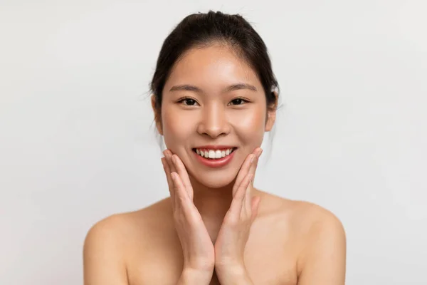 幸せな若いアジアの女性彼女の頬に触れ カメラで笑顔 韓国の女性は スキンケアの治療を楽しんで 白いスタジオの背景に立って コピースペース — ストック写真