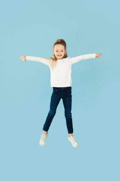 Menina Feliz Posando Médio Saltando Espalhando Braços Sobre Fundo Azul — Fotografia de Stock