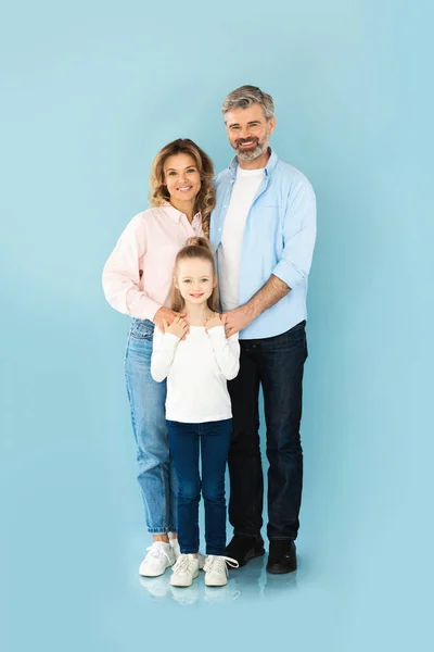 Rodzice Średnim Wieku Ściskający Swoją Córeczkę Pozującą Razem Studio Niebieskim — Zdjęcie stockowe