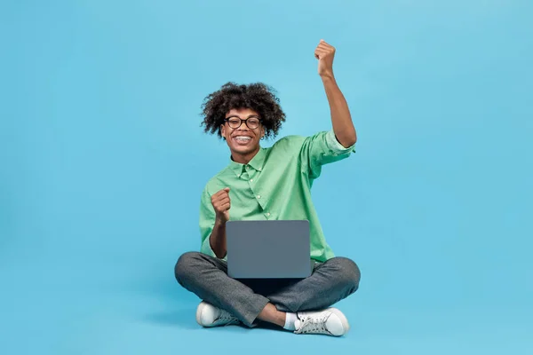 Podekscytowany Czarny Facet Używający Laptopa Trzęsący Się Radości Siedząc Niebieskim — Zdjęcie stockowe
