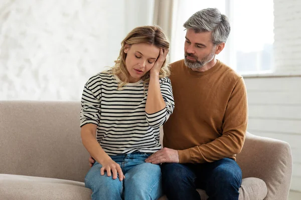 丈夫支持妻子从痛苦的偏头痛中痛苦地挣扎着 妻子坐在家里的沙发上 高血压症状 女性健康问题概念 — 图库照片