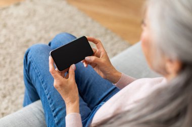 Beyaz saçlı, beyaz saçlı, yetişkin bir kadın. Ya da akıllı telefonda, içi boş bir ekranla, omuz manzaralı sohbet ediyor. covid-19 sırasında sosyal ağlar, mesafe, yeni uygulama, teklif ve reklam