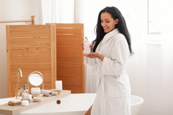 Bodycare Cosmetics. Cheerful Woman Using Body Lotion Or Liquid Soap Caring For Herself Enjoying Beauty Routine Standing In Modern Bathroom At Home. Wellness And Spa