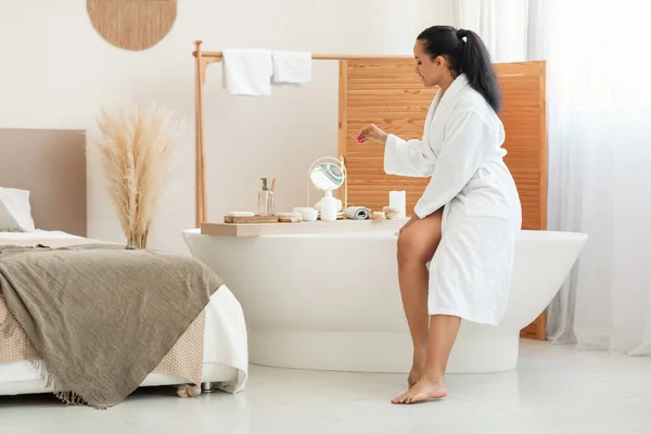 욕조에 바닷물을 관리하고 목욕을 화장품 제품을 사용하여 현대의 욕실에 앉는다 — 스톡 사진