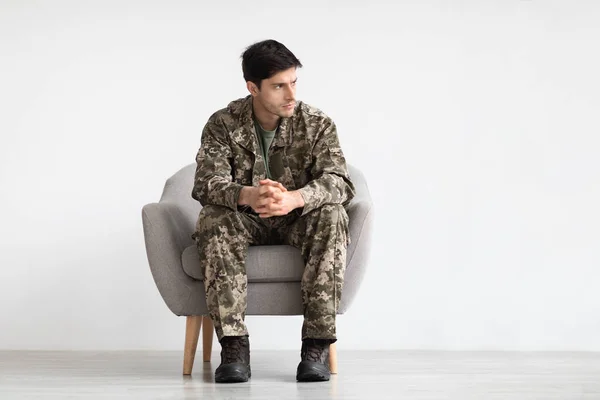 Joven Trastornado Uniforme Camuflaje Soldado Sentado Sillón Sobre Fondo Blanco —  Fotos de Stock