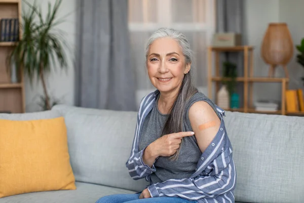 在客厅室内接种疫苗后 用灰白色的发尖在肩部贴上创可贴 微笑着欧洲的老年女性 退休人员的保健 流感疫苗和Covid 19病毒免疫接种 — 图库照片