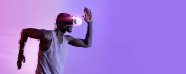 VR kulaklıklı Afro-Amerikalı adam neon ışıkta koşuyor. Sanal gerçeklik gözlüklerini kullanarak yarış ya da maratona hazırlanmak için motive olmuş zenci bir sporcu. Fütürist teknolojiler kavramı, kolaj, kopyalama alanı