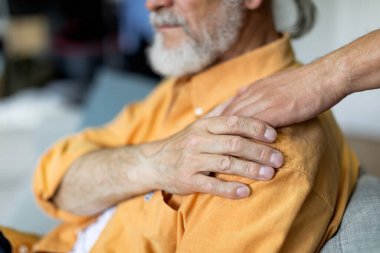 Tanımlanamayan yetişkin oğlu ve evde kıdemli babası yaşlı babasının omzuna dokunup yakın plan çekimler yapıyorlar. Yaşlılara, olgun çocuklara ve ebeveynlerin ilişki konseptine destek