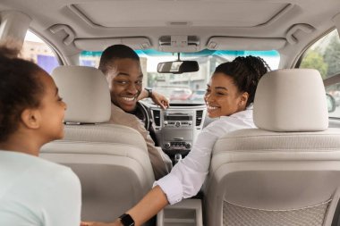 Afrika kökenli Amerikalı bir ailenin yeni arabalarında oturup birbirlerine gülümseyip yaz yolculuğunun tadını çıkarmalarını izlemek. Otomobil Kiralama ve Satın Alma Konsepti. Seçici Odaklanma