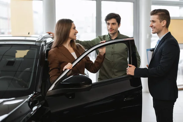 Positive Young Couple Discussing Purchase Lease New Car Auto Salesman — Stock Photo, Image