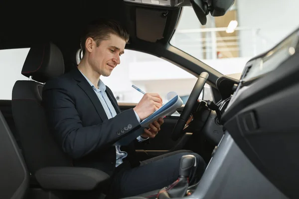Positiv Ung Bilförsäljare Sitter Inne Bil Gör Kontroll Anteckningar Provkörning — Stockfoto