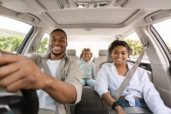 Car Sales. Cheerful Black Family Posing Sitting In New Automobile, Smiling To Camera Driving Traveling By Auto On Weekend. Road Trip Adventure Concept. Selective Focus