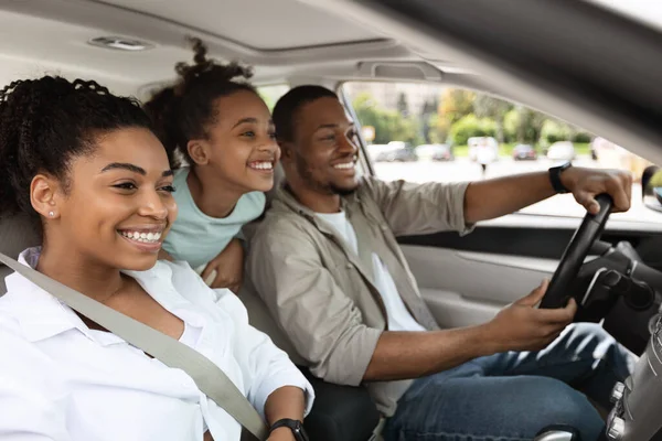 Side View Of Cheerful Family Driving A Car Having Road Trip. Parents And Daughter Sitting In Automobile Seats Smiling Looking Aside. Auto Leasing And Purchase. Selective Focus