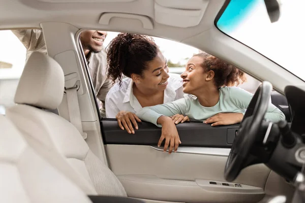 Car Dealership. Cheerful African American Family Of Three Choosing Vehicle Looking Through Window At Automobile Interior. Auto Leasing Business Concept. Selective Focus