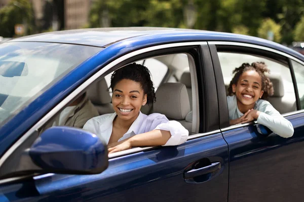 African American Family Posing Sitting In Blue Car In Urban Area. Parents And Daughter Driving New Auto Enjoying Ride Smiling To Camera. Automobile Purchase And Rent Concept. Selective Focus