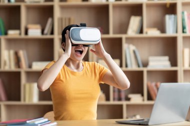 VR gözlüklü heyecanlı genç Çinli kadın çevrimiçi oyunlar oynuyor, içerideki genişletilmiş dünyayı keşfediyor. Evde eğlence için dijital aygıtlar, covid-19 salgını nedeniyle sanal gerçeklik