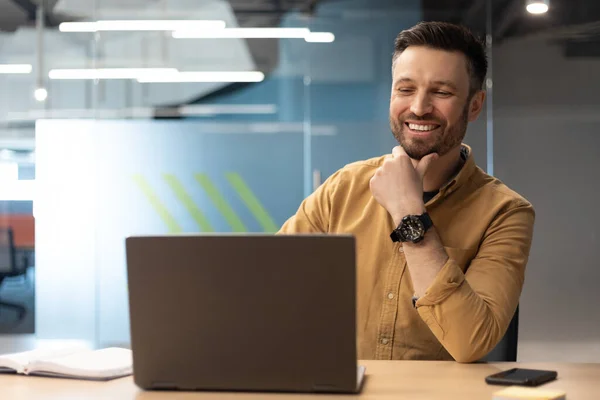 Cheerful Business Man Using Laptop Touching Chin Sitting Workplace Indoors — Foto de Stock