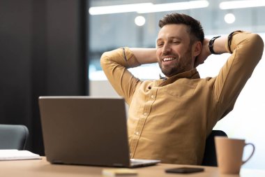 Cheerful Business Man Using Laptop Holding Hands Behind Head Relaxing Resting Sitting In Chair At Workplace In Modern Office. Successful Career And Entrepreneurship Concept
