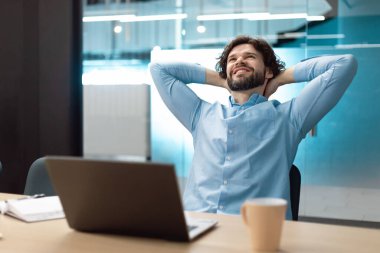 Ara veriyoruz. Gülümseyen orta yaşlı adam sandalyede dinleniyor, masada oturuyor ve ofisteki bilgisayarını kullanıyor. Mutlu olgun bir erkek iş yerinde arkasını yaslıyor, işinden zevk alıyor, tatmin oluyor.