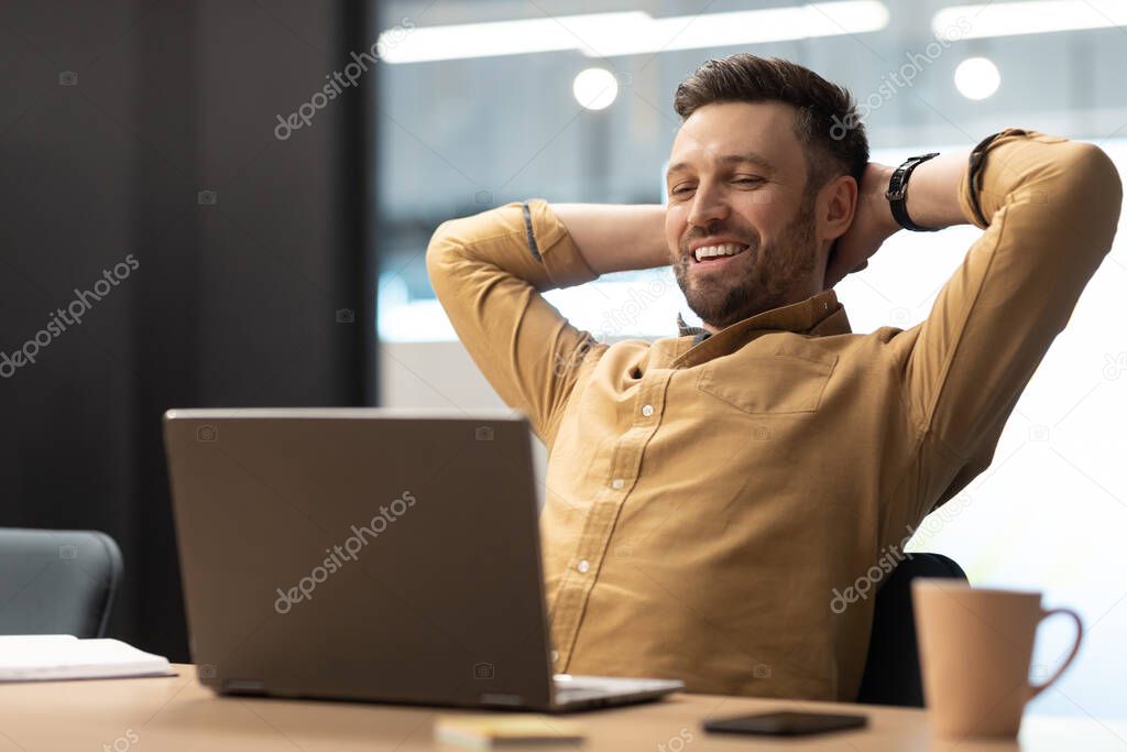 Cheerful Business Man Using Laptop Holding Hands Behind Head Relaxing Resting Sitting In Chair At Workplace In Modern Office. Successful Career And Entrepreneurship Concept