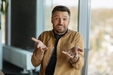 İş adamı konuşuyor ve hareketli bir şekilde kameraya bakıyor. İletişim kuruyor ve modern ofiste oturuyor. Girişimcilik ve İletişim Konsepti