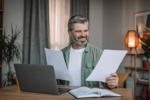 Smiling Caucasian Senior Man Beard Works Laptop Documents Living Room — Stok fotoğraf