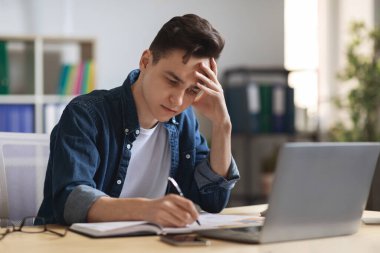 Ofiste otururken Not Defterine Yazan Meşgul Genç Erkek Girişimci, Milenyum İşadamı Planlama Programı, Gündemde Bilgi Notları, Boş Alan ile Yakın Çekim