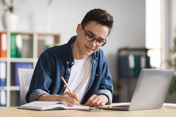 Young Male Office Employee Taking Notes While Working With Laptop Computer In Office, Millennial Businessman Planning Working Schedule Or Noting Down Information From Internet, Copy Space