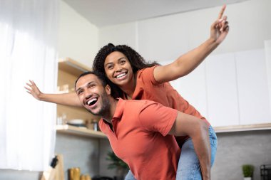 Mutlu, genç, Afro-Amerikan bir erkeğin kadını kollarına almasına ve mutfak içinde eğlenmesine sevindim. Çiftler evlerinde boş zamanlarında eğleniyorlar. Duyguları, aşkı ve ailesi karantina altında.